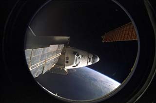 View of the shuttle forward Crew Compartment as seen from the Mir space station Base Block module. A Mir solar array can be seen just above the orbiter. 